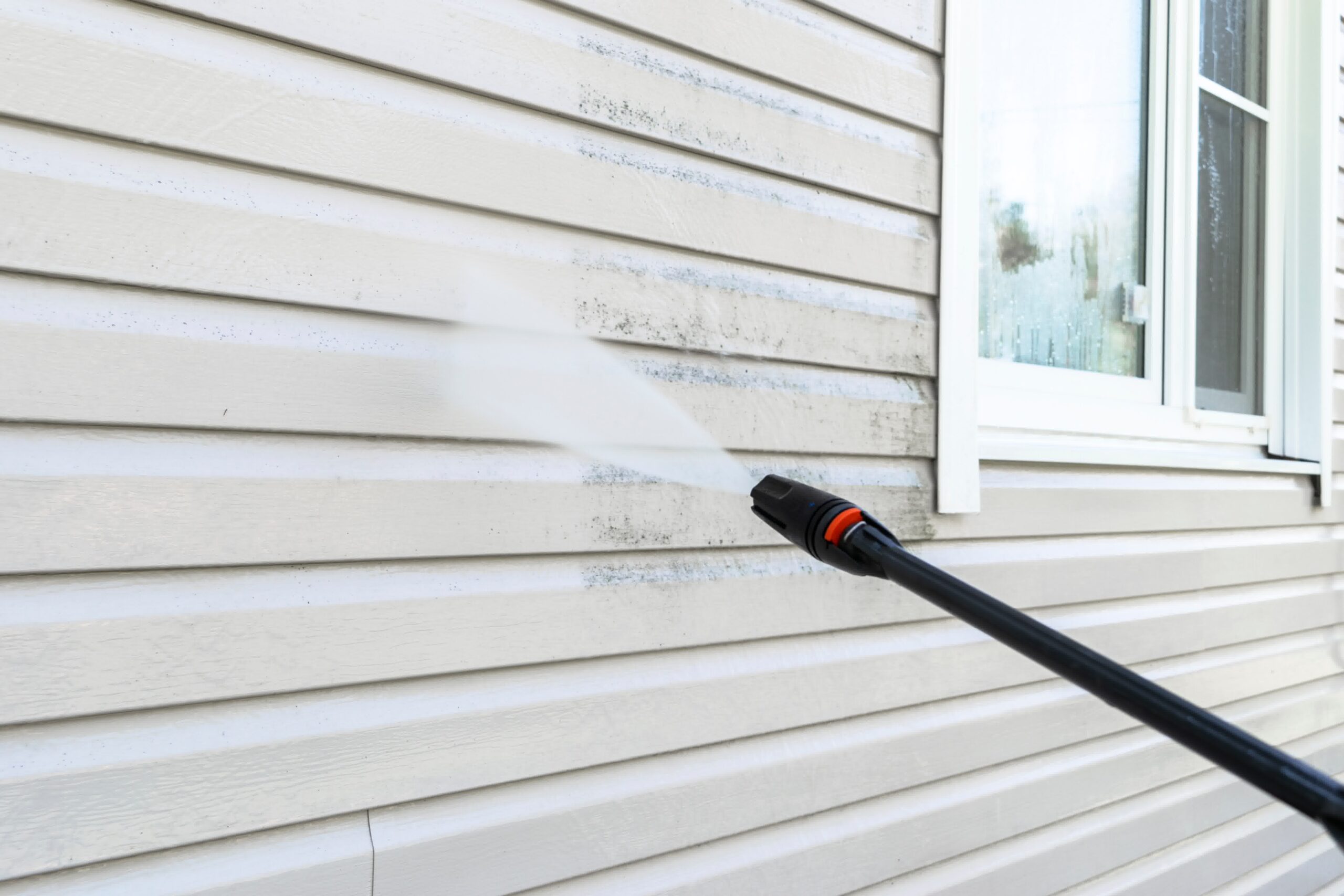 A pressure washer knocking the gunk and grime off a home's surface.