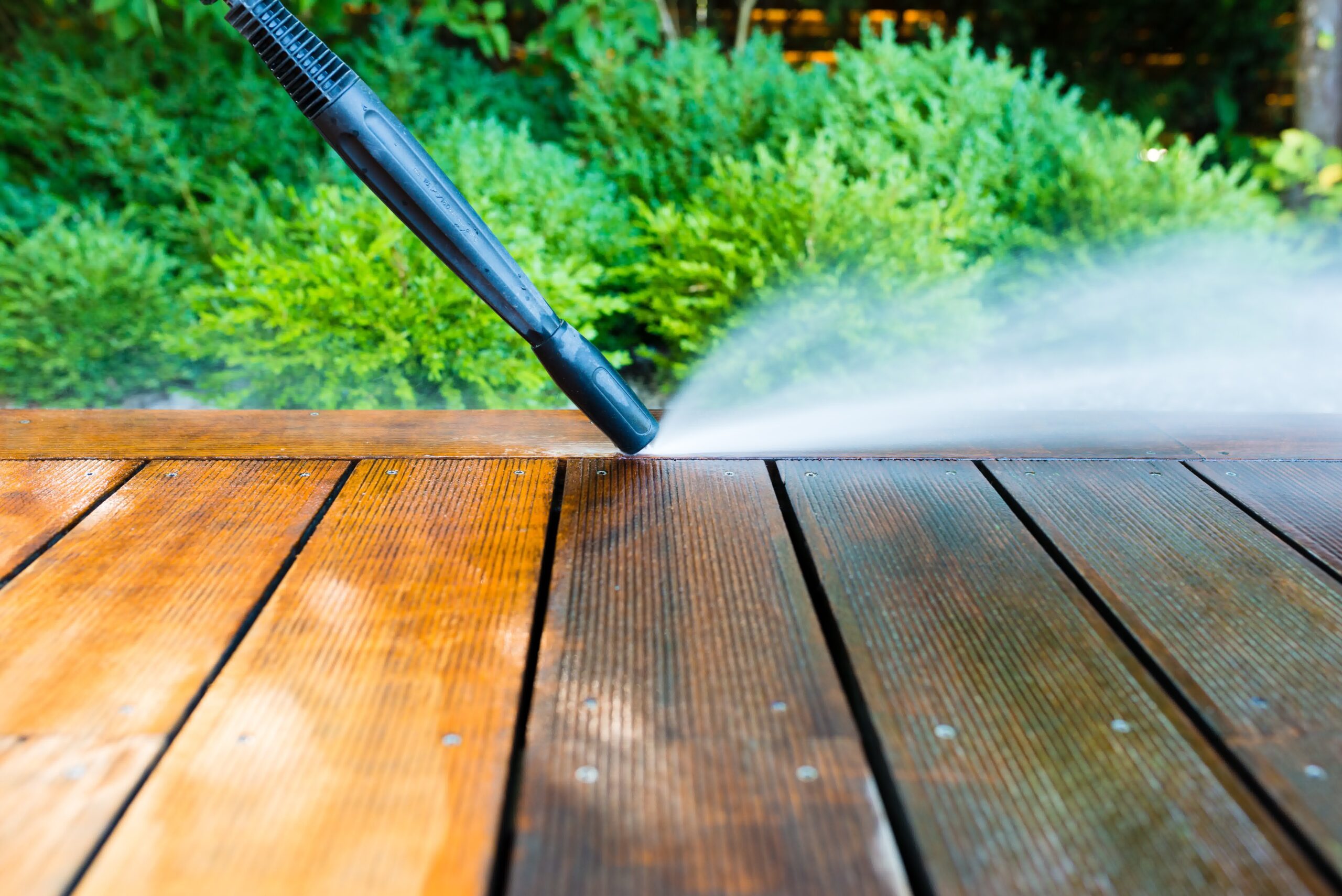 Close up shot a wooden surface being pressure washed.