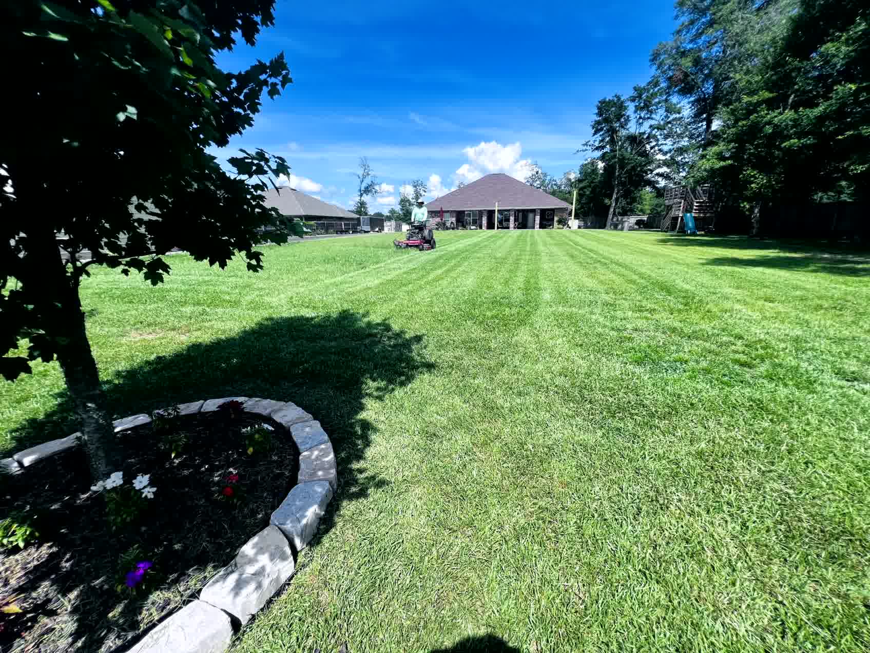 The Secret to a Lush Lawn All Year Long - ProMow Lawn & Landscaping Our crew member mowing a well-maintained lawn for a satisfied client, showcasing professional service in action.